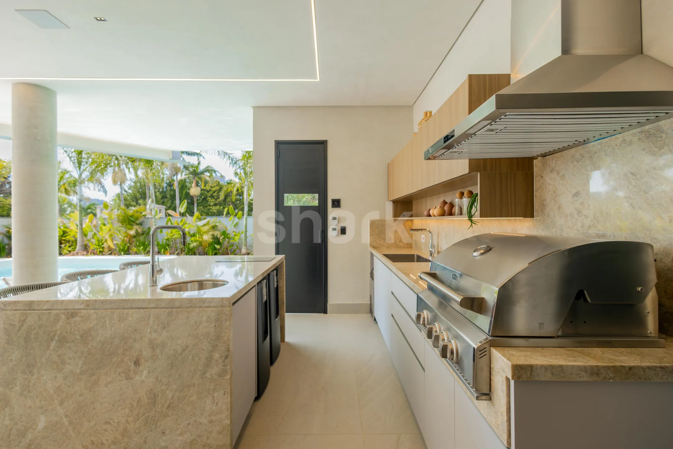 Cozinha gourmet externa com ilha de mármore e churrasqueira