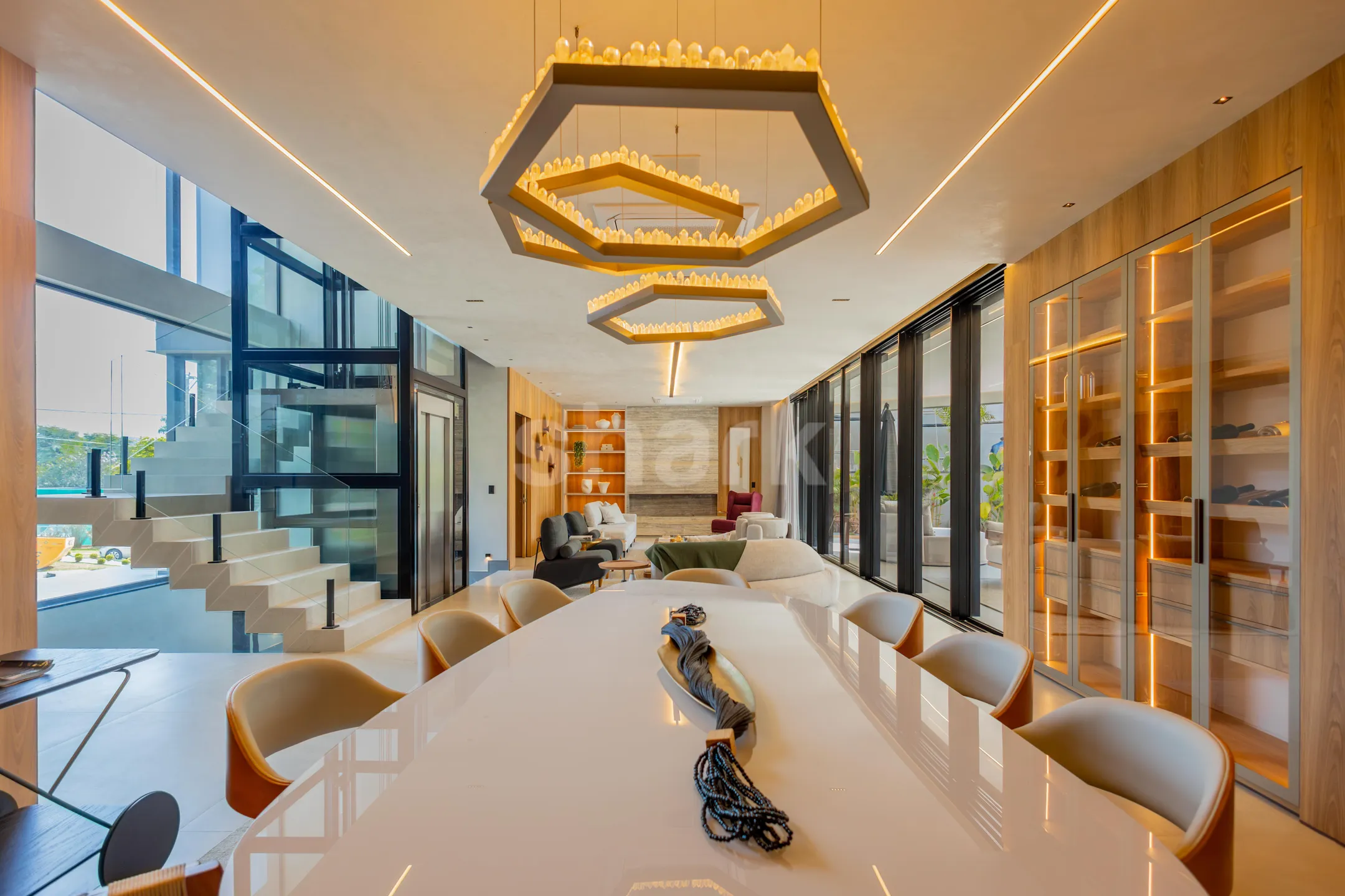 Sala de jantar com pendentes hexagonais e o elevador panorâmico ao fundo