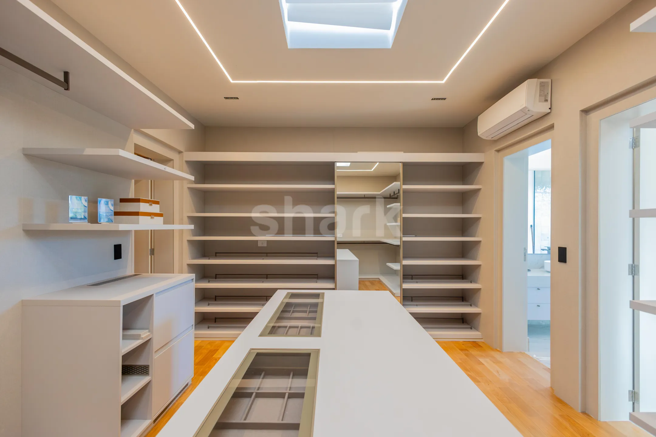 Closet da suíte master com ilha central e claraboia
